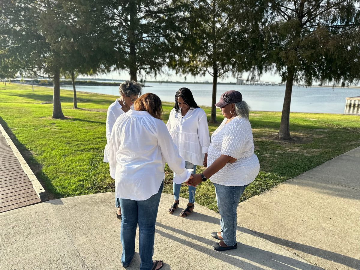 Four women from the Girl Boss Prays family holding hands and praying together.